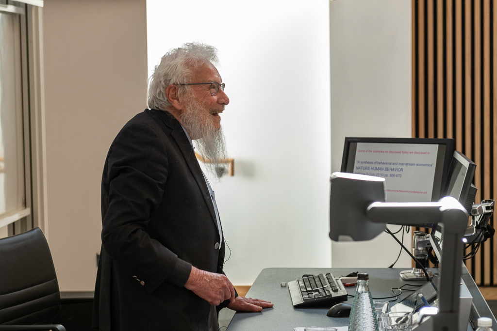 Professor Robert Aumann stands behind a computer screen as he gives a lecture