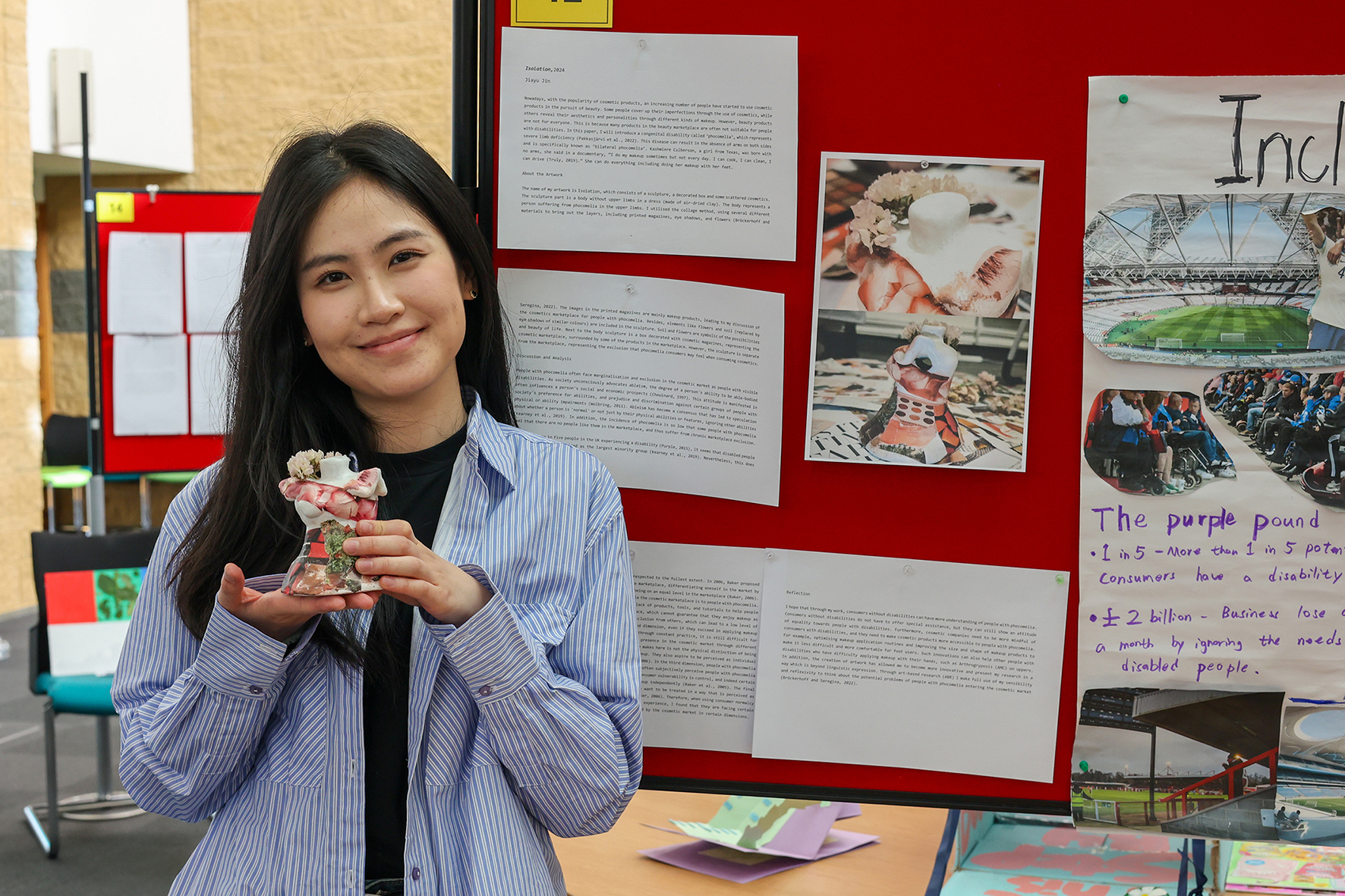 Student Jiayu Jin holds her artwork, a clay torso speaking to experiences for people born with no limbs