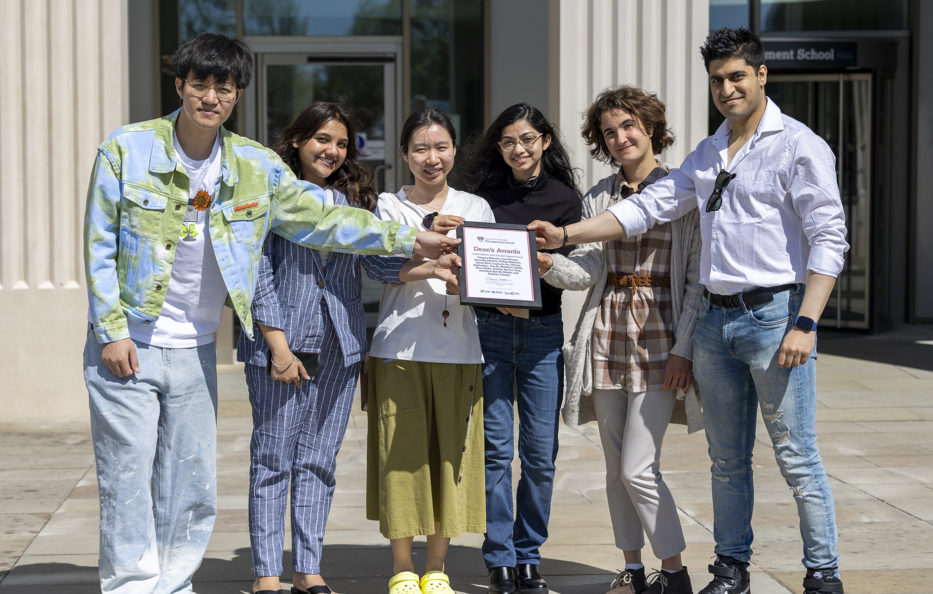Members of the LUMS EQUIS 2023 Student Report Group hold their LUMS Dean's Award certificate outside the Management School building