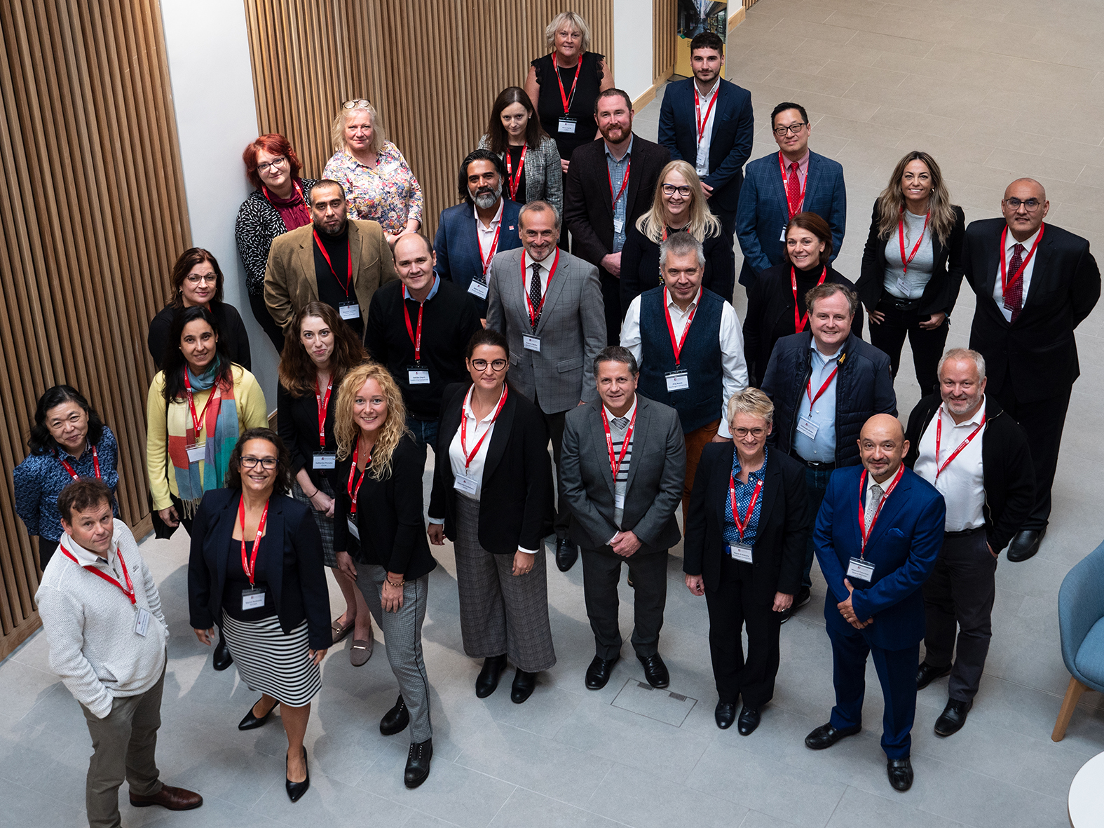Members of the International Partnership of Business Schools looking up at the camera while stood together in a hall in Lancaster University Management School