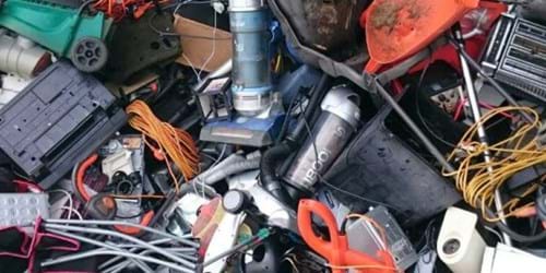 A jumble of electronic waste, including wires and vaccuum cleaners, at a civic amenity site
