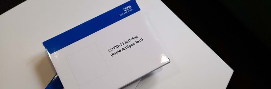 Covid LFD test kits in white packaging with blue NHS banner along the top