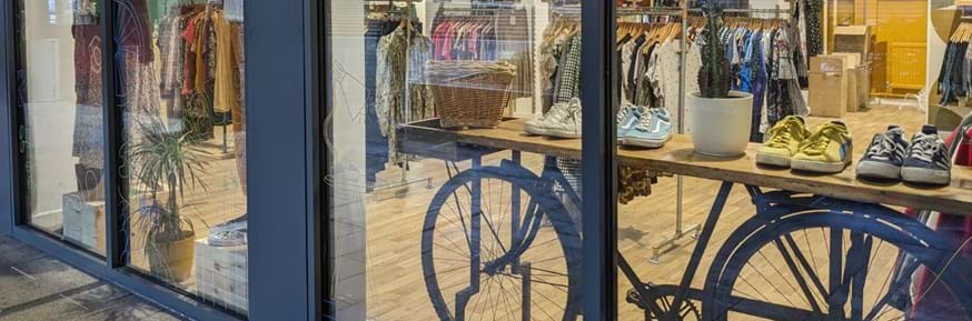 Shop front display of a bike, shoes, clothes & plants