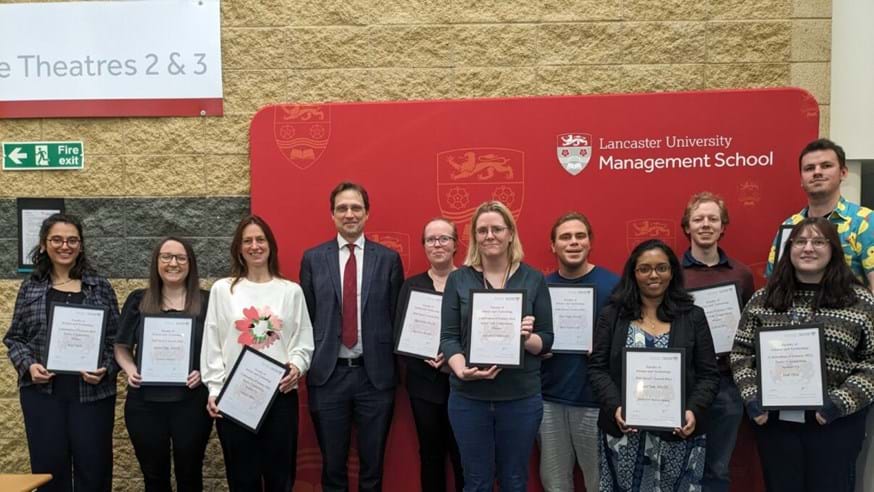 Ten student prize winners holding their certificates with Dean Professor Pete Atkinson.