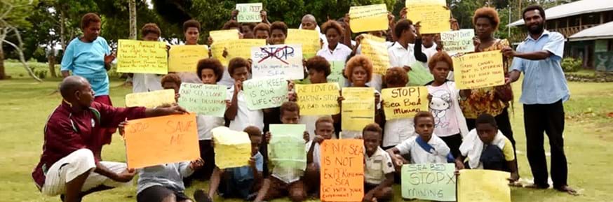 A group of residents and school children in Papua New Guinea wit homemade signs protesting against deep sea mining