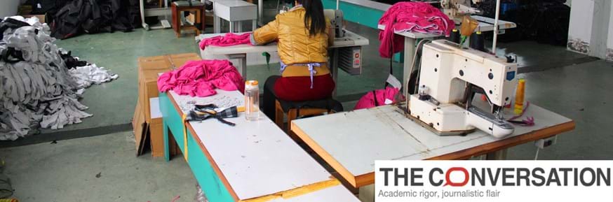 A woman working at a sewing machine in a clothing factory