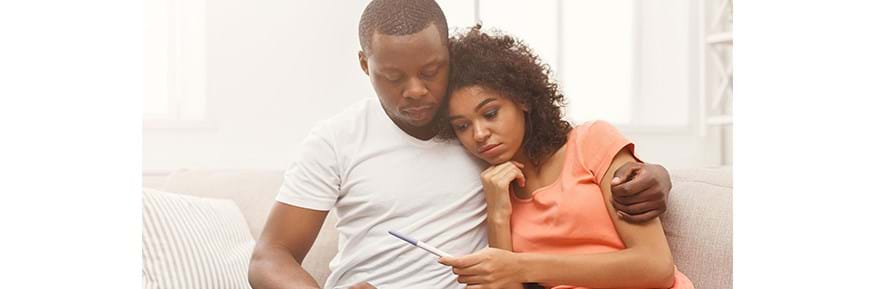 Disappointed couple looking at negative pregnancy test