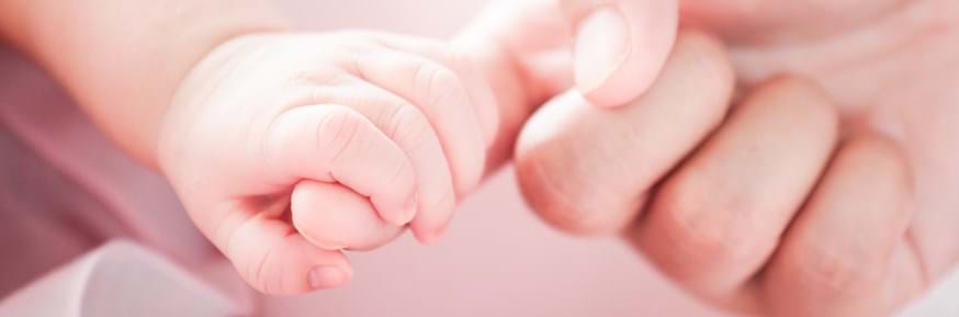 A baby hand gripping the finger of a parent