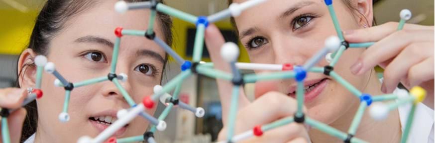 Two female students studying a model of a chemical compound