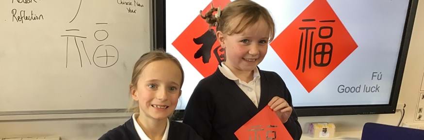 Children holding up a red piece of paper with the Chinese character 'fu' which means 'good luck' in Mandarin