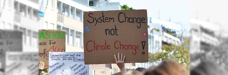 Demonstrator holding up a placard calling for system change not climate change