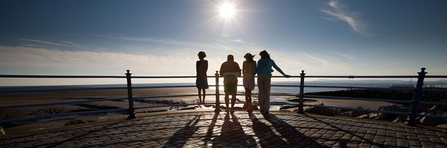 four people standing looking out over Morecambe bay beach