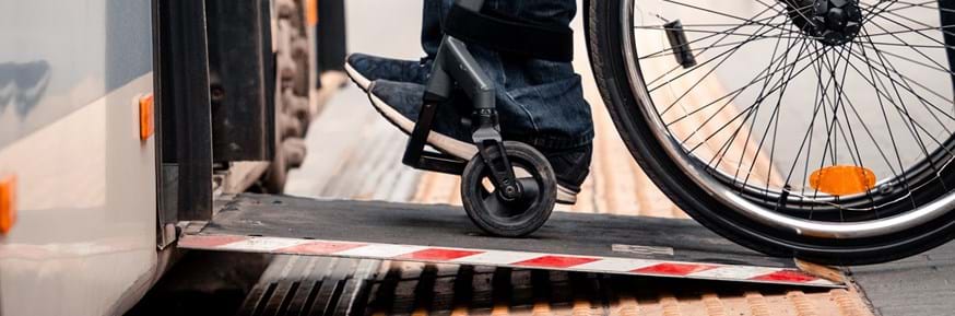 A cropped image showing a man in a wheelchair using a ramp to get on a train