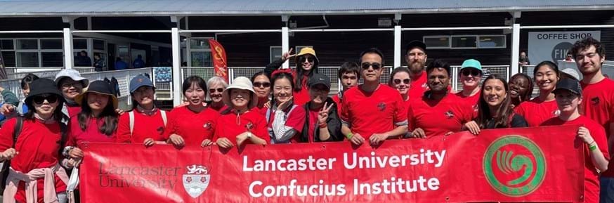 The Lancaster University Confucius Institute team holding a red banner that says ' Lancaster University Confucius Institute'