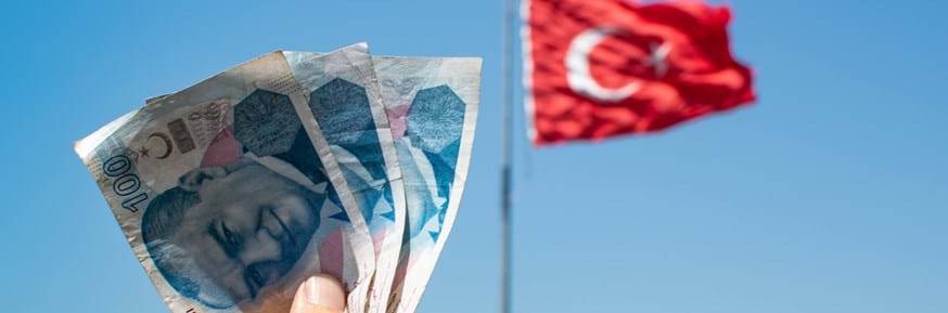 Turkish lira held up in front of a Turkish flag