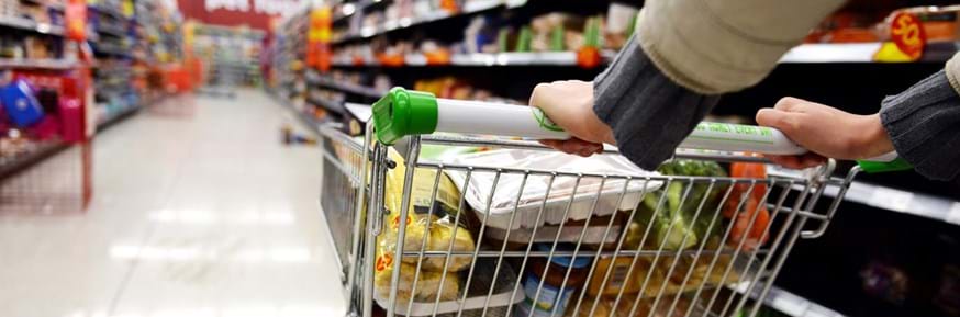Close up of a shopping trolley being pushed down a supermarket aisle