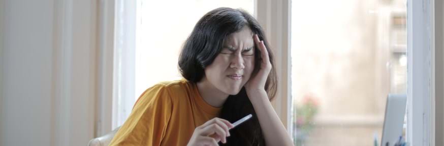 A woman with a migraine holds her head while in pain