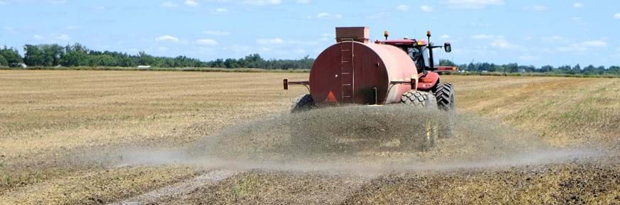 A tractor spreads fertiliser on an open field