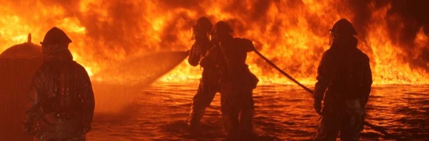 Firefighters in full protective equipment tackle a raging orange blaze 