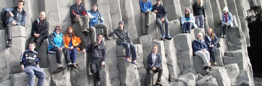 Students of all genders sit on basalt rock columns