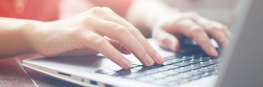An image of someone's hands typing on a laptop