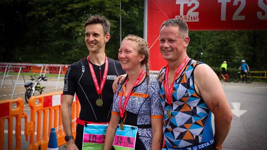 Three people posing for a photo wearing Triathlon medals after the 2023 Triathlon