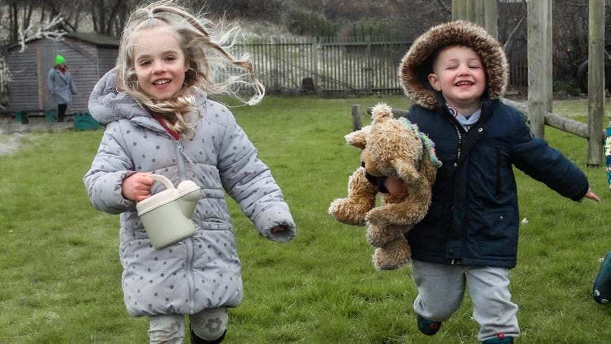 Two Children running with Eden Bear