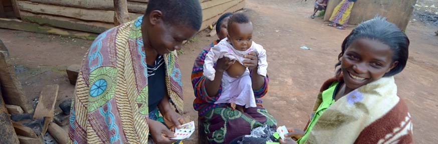 Young Malawian women playing cards - one young woman holding a baby