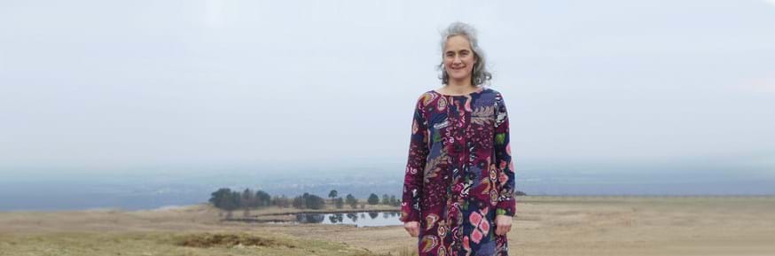 Professor Jo Knight standing in front of a lake surrounded by trees