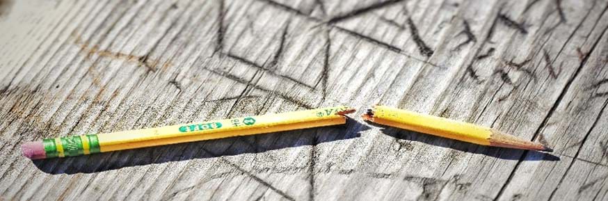 A broken yellow pencil on a grey surface