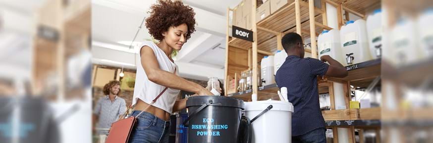 Woman serving herself to eco dishwasher powder from a big tub
