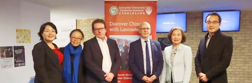Six people stood in front of a Lancaster University Confucius Institute banner smiling at the camera.