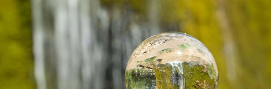 Clear glass ball on a rock reflecting the environment.