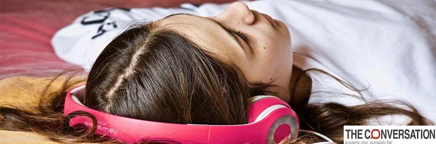 A young woman lying down listening to headphones