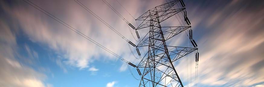 An image of an electricity pylon set against a blue, cloudy sky