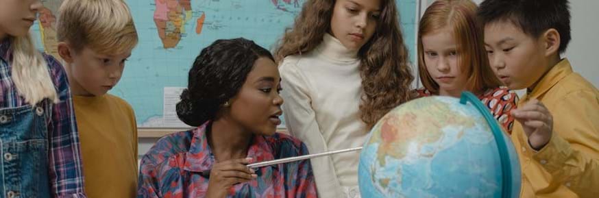 Children and their teacher examining a globe