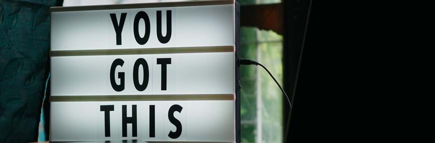 A lightbox is on a desk next to a laptop and a notebook, displaying the words 'you got this'.