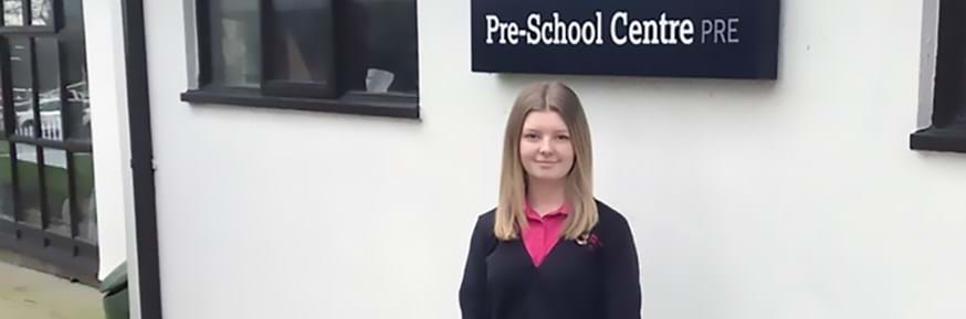 Chloe Catterall, Pre-School Support Assistant and apprentice standing outside of the Pre-School Centre.