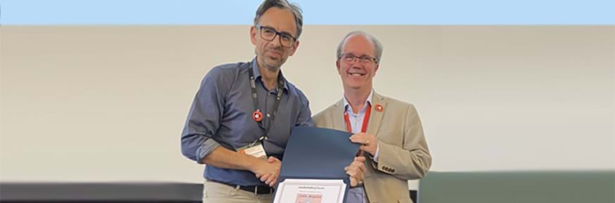 IIF President, George Athanasopoulos (left), presenting a fellowship certificate to Professor Boylan. Both are smiling at the camera as George is handing a certificate to John.