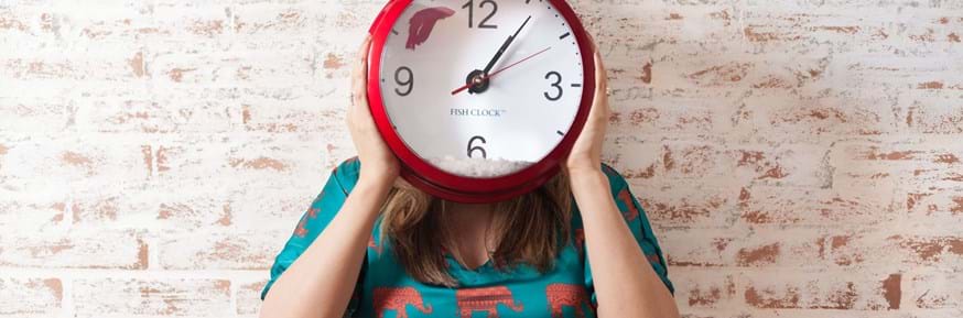 Image of a woman holding a large clock against her face