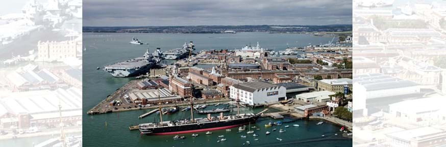 Aerial view of the Royal Navy Dockyard, Portsmouth, showing large and majestic old yacht and Royal Navy aircraft carriers in the background