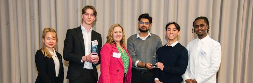 A line up photograph of the Tech Titans Competition winners from Lancaster University with CEO of TechSkills. From  L-R: Siwon Baik, Will Sargent, Kelly Nicholls (CEO of TechSkills), Murtaza Ghous, Kei Sasaki, Hamza Mahmoud