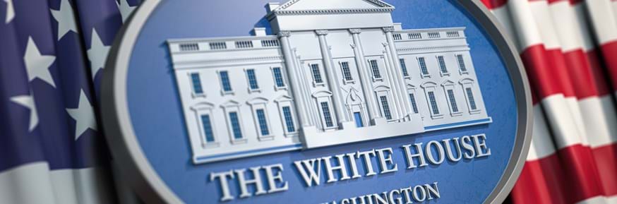 A plaque of the White House, set against an American flag in the background