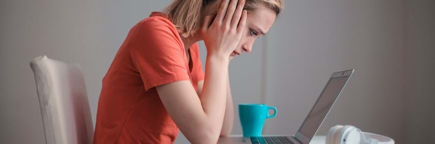 Woman with head in hands in front of laptop 